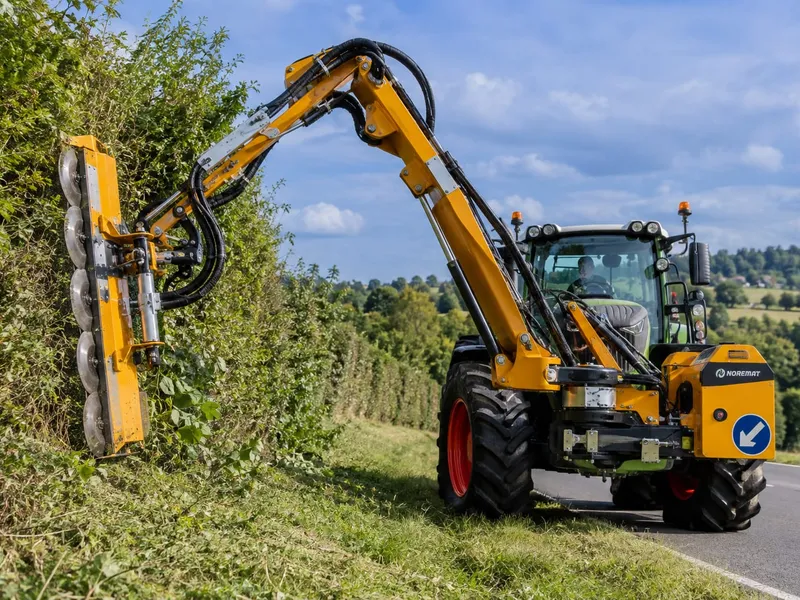 Tracteur équipé d'un lamier à disques taillant une haie en bord de route